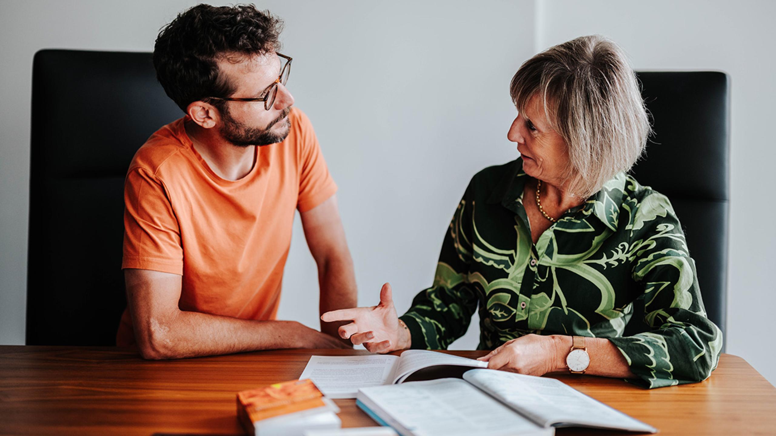 Man en vrouw overleggen aan bureau.
