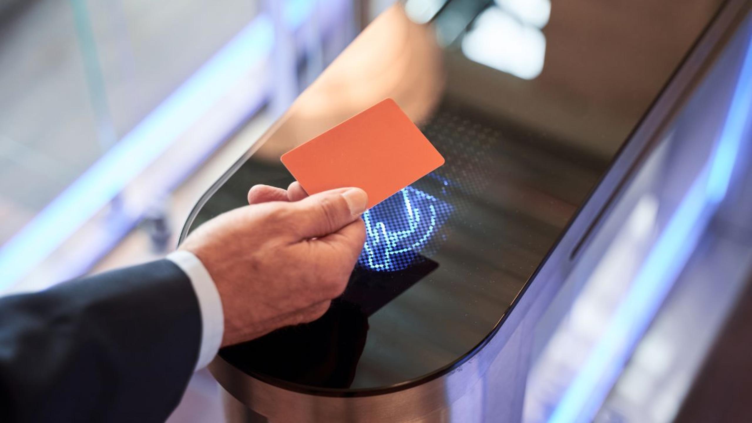 Close-up hand houdt badge boven badgelezer.  
