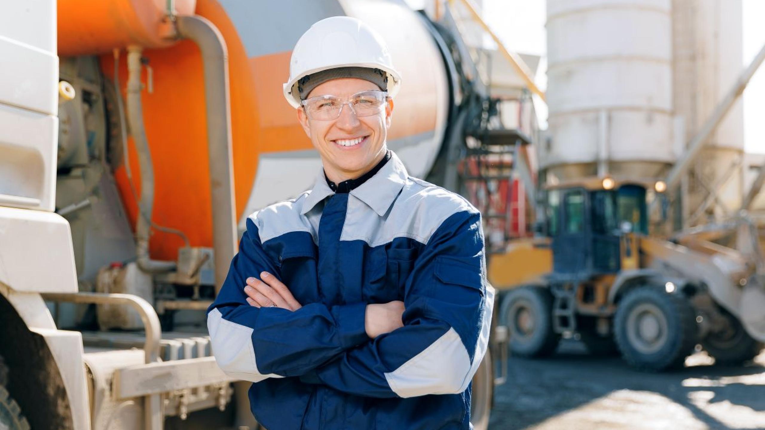 Man met helm staat voor betonmixer.