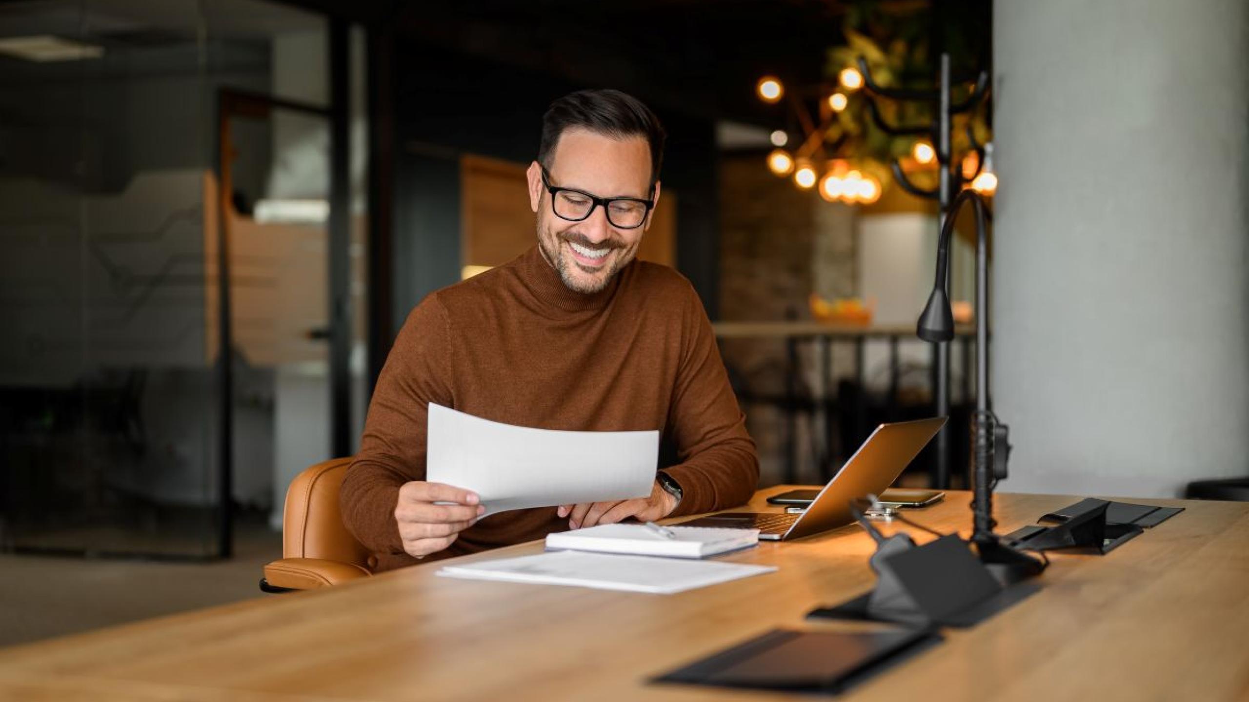 Blije man leest document in een trendy kantoor