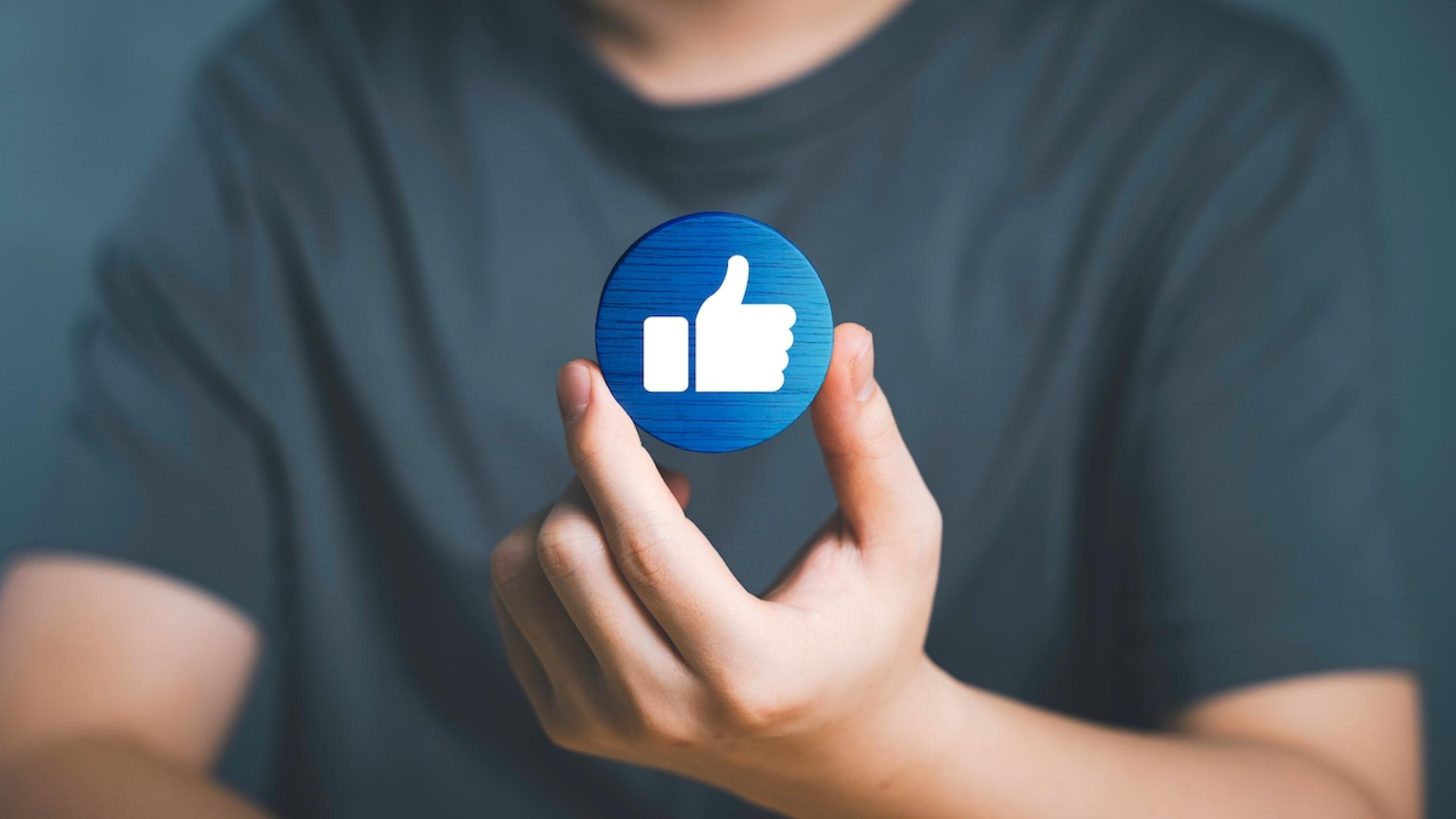 Close-up handen met fysieke 'thumbs up' emoji.