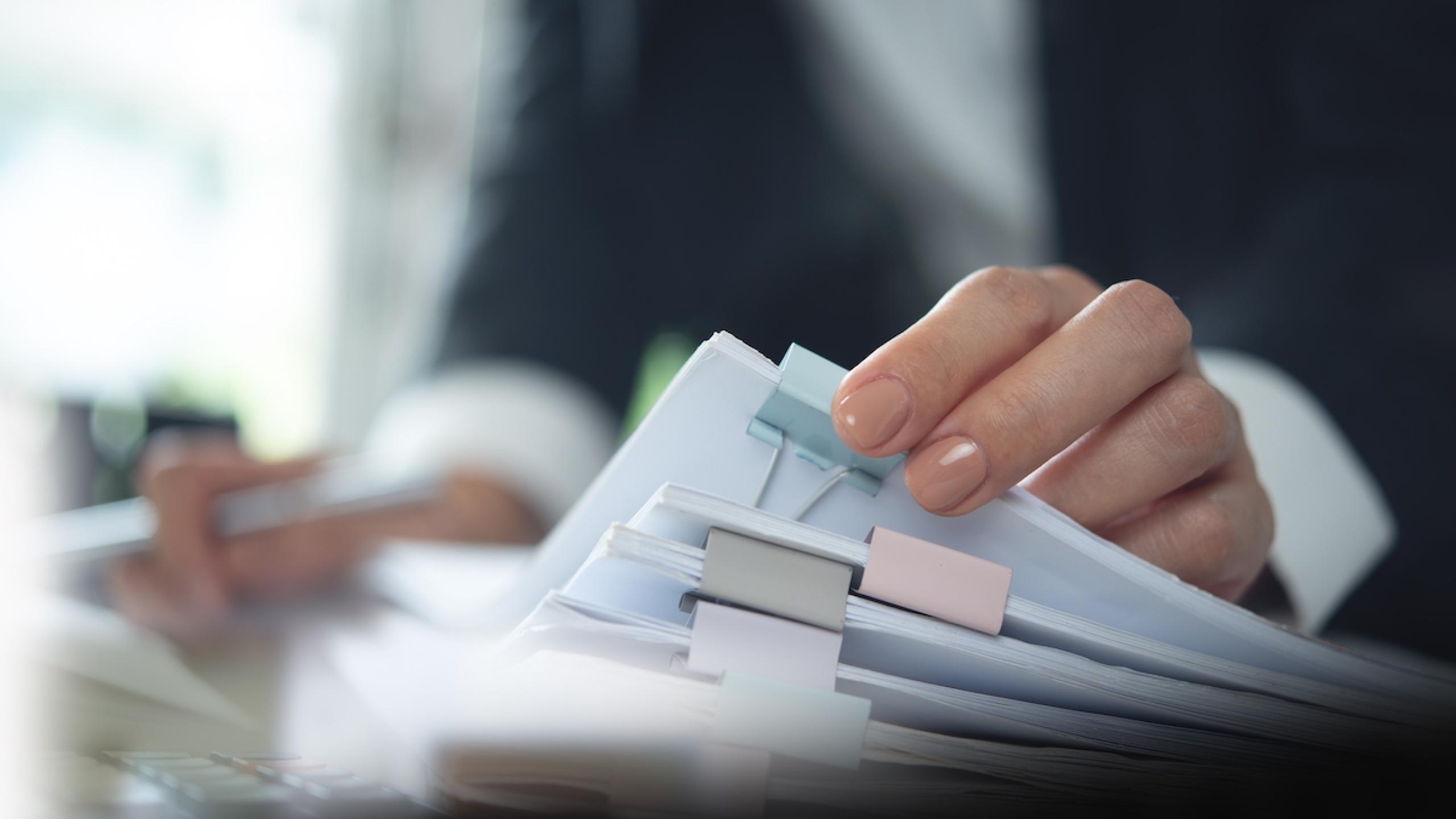 Close-up handen met stapel papieren.