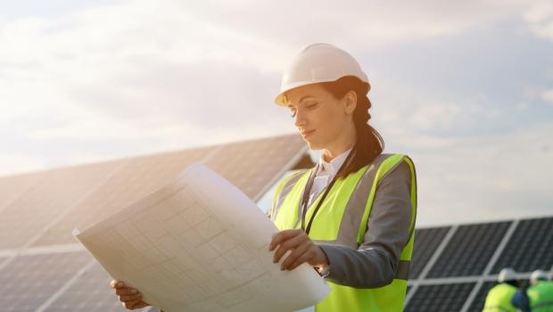 Ingenieur houdt plannen vast naast fotovoltaïsche panelen.